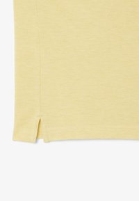 Tessuto di cotone giallo con una finitura texturizzata. Il bordo inferiore presenta uno spacco laterale, aggiungendo un sottile dettaglio di design.