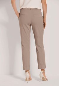 Beige op maat gemaakte broeken met een slim fit, rechte snit en een lichte tapering bij de enkels. Voorzien van twee achterzakken en gedragen met lichtgekleurde hakken.
