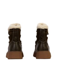 Braune Lederstiefeletten mit weißem Futter aus Kunstfell, Gummisohle und charakteristischer horizontal gerippter Textur an der Ferse. Zwei seitliche Riemen sichtbar.