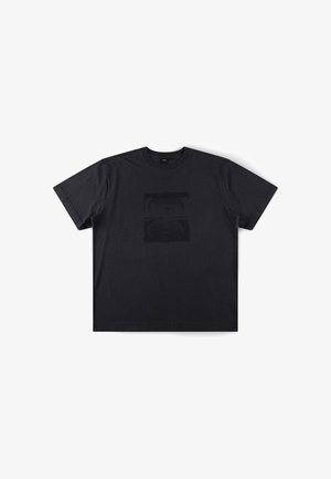 T-shirt noir à manches courtes avec col rond, graphique rectangulaire discret en relief sur la poitrine, posé à plat sur fond blanc.