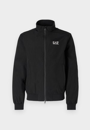 Melnā, vieglā bumbiera tipa jaka ar rāvējslēdzēju, ribotām piedurknēm un apkakli. Priekšā augšējā kreisajā pusē ir EA7 logotips.