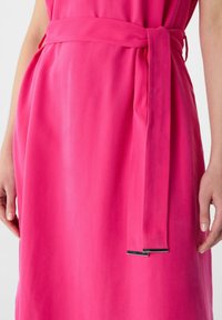 Rosa Kleid aus einem glatten, leichten Stoff. Mit einem gebundenen Taillengürtel und silbernen Hardware-Details. Schlichtes und elegantes Design.