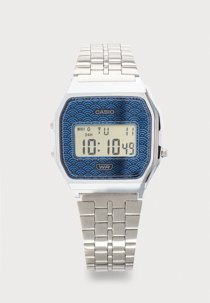 Ψηφιακό ρολόι Casio με ασημένιο μεταλλικό λουράκι, μπλε καντράν με σχέδια, δείχνει την ώρα 10:10:49, ημέρα Τρίτη, ημερομηνία 11.