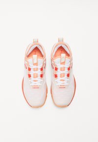 White athletic shoes with orange accents, mesh upper, lace-up design, logo on tongue, and textured sole.