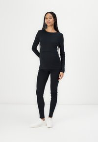Ensemble composé d'un haut noir à rayures côtelées à manches longues et d'un legging ajusté, associé à des baskets blanches. L'ensemble présente un col rond et une texture lisse.