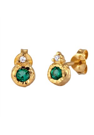 Des boucles d'oreilles en or présentant un design texturé avec une gemme verte et une petite pierre claire au-dessus. La forme générale est arrondie et polie.