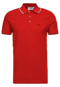 Röd pikétröja i bomull med korta ärmar, ribbat krage, treknappars placket och vit kant på krage och ärmar. Har logotyp på bröstet.