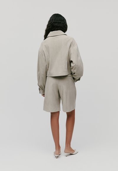 Lichtgrijze cropped jacket met oversized mouwen, gecombineerd met bijpassende shorts. Glad suède materiaal, eenvoudig ontwerp en minimalistische stijl.