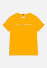 Żółta bawełniana koszulka z krótkim rękawem z białym napisem "TOMMY HILFIGER EST. 1985" i logo z przodu. Standardowy krój z okrągłym dekoltem.