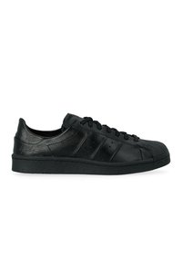 Sneaker nera bassa con lacci, punta testurizzata, strisce laterali perforate e logo in rilievo discreto sul tallone.