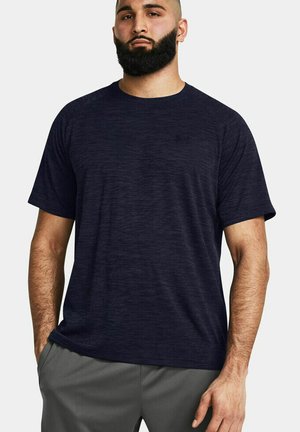 T-shirt bleu marine à manches courtes avec un motif texturé, col rond et coupe confortable, associé à un pantalon gris, porté par un modèle masculin.
