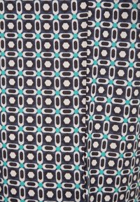 Tessuto a fantasia con un design geometrico caratterizzato da forme alternate in blu scuro, bianco e turchese, con un aspetto tessile testurizzato.
