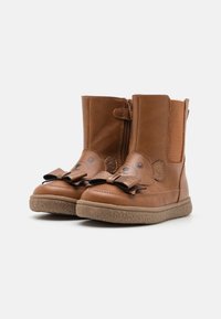 Brune lær ankle boots med en stoffsløyfe, bjørnefacedetaljer og glidelås på siden. Teksturert gummisåle for grep.