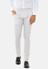 Pantaloni a quadri grigi chiari con vestibilità slim, dotati di chiusura a bottone, tasche laterali e una texture sottile. Abbinati a mocassini neri.