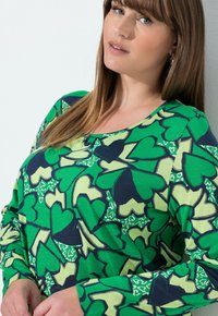 Langærmet skjorte i et grønt og navy farveskema med et hjerteprintmønster, rund halsudskæring og blød stoftekstur.