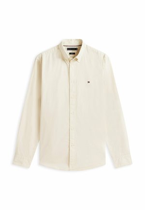 Chemise beige à manches longues avec boutons, col et petit logo Tommy Hilfiger sur la poitrine gauche.