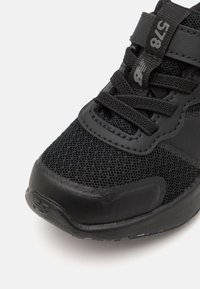 Chaussure de sport noire avec une tige en mesh, une semelle en caoutchouc et des lacets en nylon. Inclut un col rembourré et une pointe renforcée pour la durabilité.