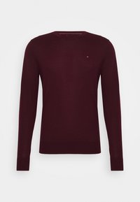 Bordeauxroter Pullover mit langen Ärmeln aus glattem Strickstoff. Verfügt über einen Rundhalsausschnitt und ein kleines Logo auf der Brust. Klassische Passform mit gerippten Bündchen.