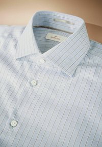 Lyseblå ternet skjorte med button-down krave, der har et rutenetmønster, hvide knapper og et blødt, tekstureret stof.