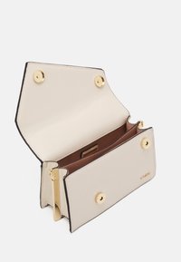 Beżowy skórzany portfel ze złotymi okuciami, wyposażony w zapięcie na zatrzask, dwie przegródki oraz brązową podszewkę wewnętrzną. Krawędzie są nieco ciemniejsze.