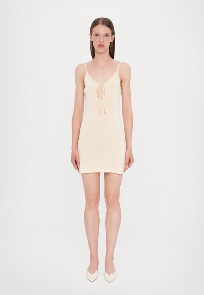 Light beige sleeveless dress with a V-neck and drawstring detail at the center. Smooth, fitted fabric with a knee-length cut. Minimalist design.