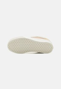 White sneaker sole featuring a textured, rubberized base with a diamond pattern, designed for improved grip and stability.