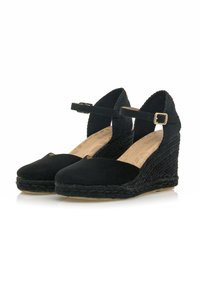Espadrillas a zeppa nere con una morbida tomaia in suede, cinturino alla caviglia con fibbia e suola in juta intrecciata. Punta rotonda e dettagli in tessuto strutturato.