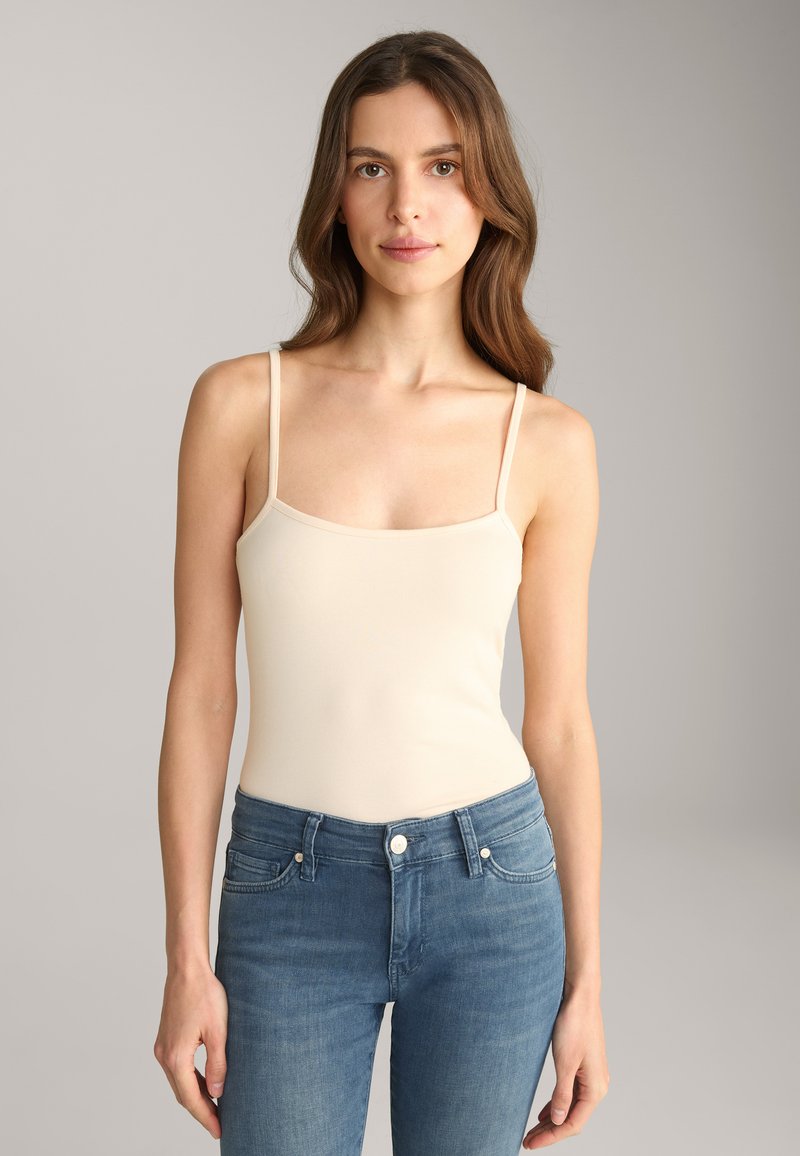 Beige tanktop met dunne bandjes en een vierkante halslijn, gecombineerd met slim-fit blauwe spijkerbroeken. Glad textuur, casual ontwerp.