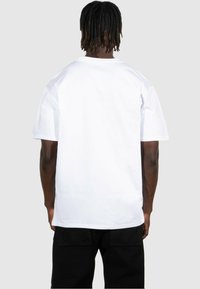 Vit bomullströja med avslappnad passform, korta ärmar och rundad halsringning. Har en mjuk struktur och inga synliga grafiska tryck eller mönster.