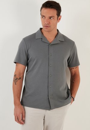 Short-sleeve gray shirt with a textured fabric, button-down front, and a wide collar. Features a casual fit and subtle accents.