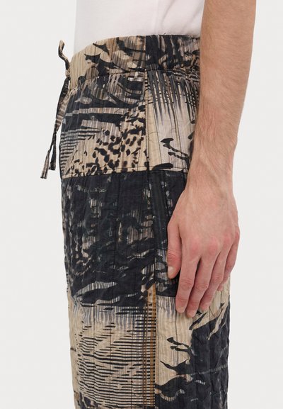 Breezy patterned shorts in beige, black, and green tones; features a drawstring waist, textured fabric, and side slit for added mobility.