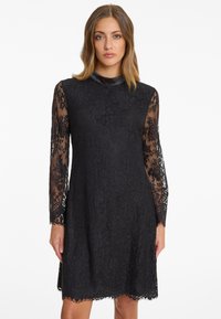 Black lace dress featuring long sheer sleeves, a round neckline, floral pattern, scalloped hem, and solid black lining.