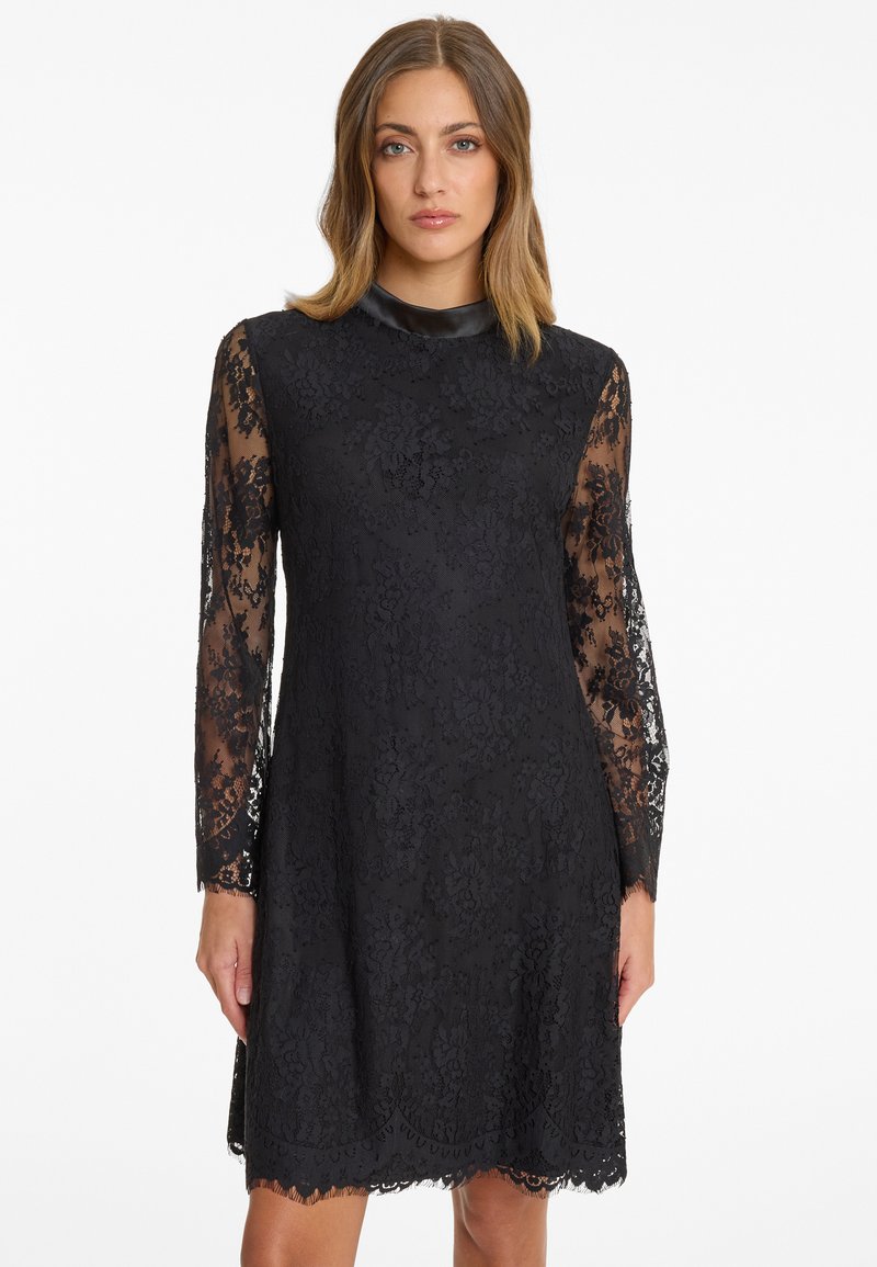 Black lace dress featuring long sheer sleeves, a round neckline, floral pattern, scalloped hem, and solid black lining.