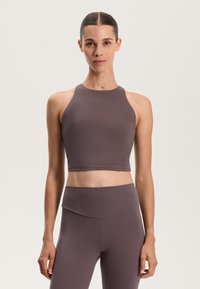 Hnedý športový crop top s vysokým výstrihom a dizajnom racerback, vyrobený z hladkej, elastickej tkaniny. Spárovaný s vyhovujúcimi legínami s vysokým pásom.
