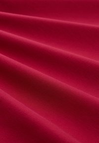 Tiefroter Stoff mit einer glatten Textur, der sanfte Falten und ein leicht mattes Finish aufweist. Das Material wirkt weich und biegsam.