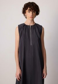 Abito senza maniche di colore grigio scuro con scollatura arricciata e chiusura centrale con zip. Realizzato in tessuto liscio con texture morbida e vestibilità comoda.