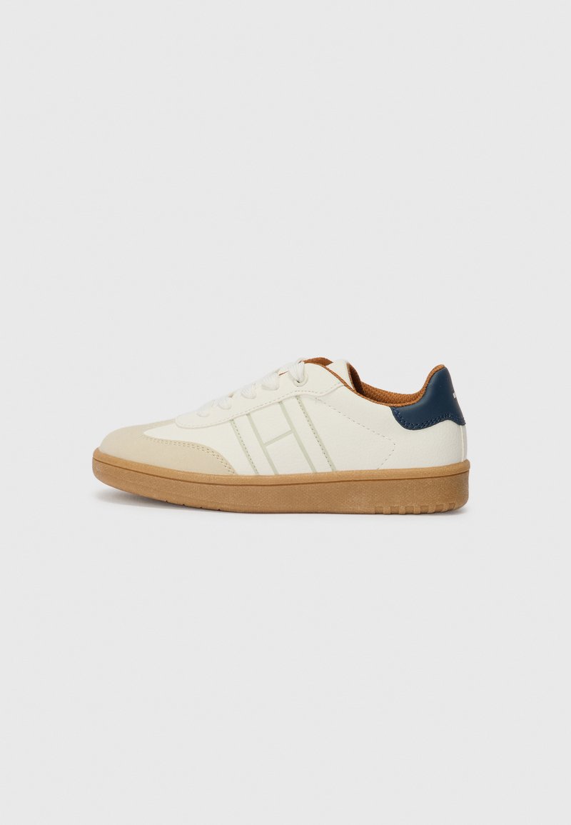 Weißer Sneaker mit Obermaterial aus glattem Leder, grünen Akzenten, Baumwollschnürsenkeln, Gummisohle und einem kontrastierenden dunkelblauen Fersenbereich.