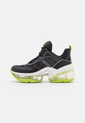 Czarny i neonowo-zielony sneaker Michael Kors z przezroczystą podeszwą z powietrznym cushionem i sznurowanym designem, zaprezentowany na białym tle.
