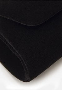Sort fleece tæppe med en glat tekstur, foldet kant og afrundede hjørner, der viser blødt materiale uden mønstre eller metaldele.