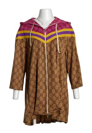 Sudadera larga marrón con cremallera, con patrón monograma GG marrón, franjas en forma de chevron moradas y amarillas en el pecho, y mangas tres cuartos en un maniquí.