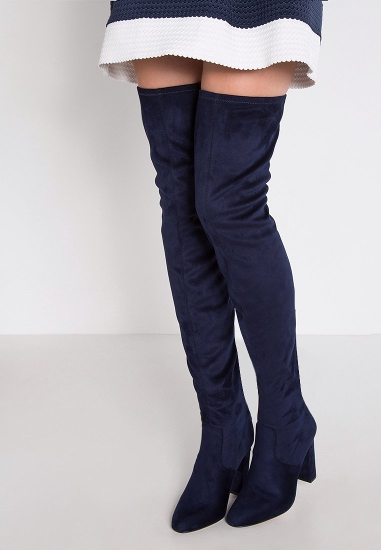 Bottes marine en daim sur le genou, dotées d'un talon épais et d'un design ajusté pour une silhouette élégante.