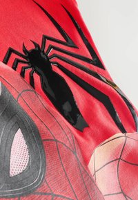 Červené tričko z látky s designem Spider-Mana, s lesklými černými detaily pavouka a pavučinovými vzory v černé a šedé.