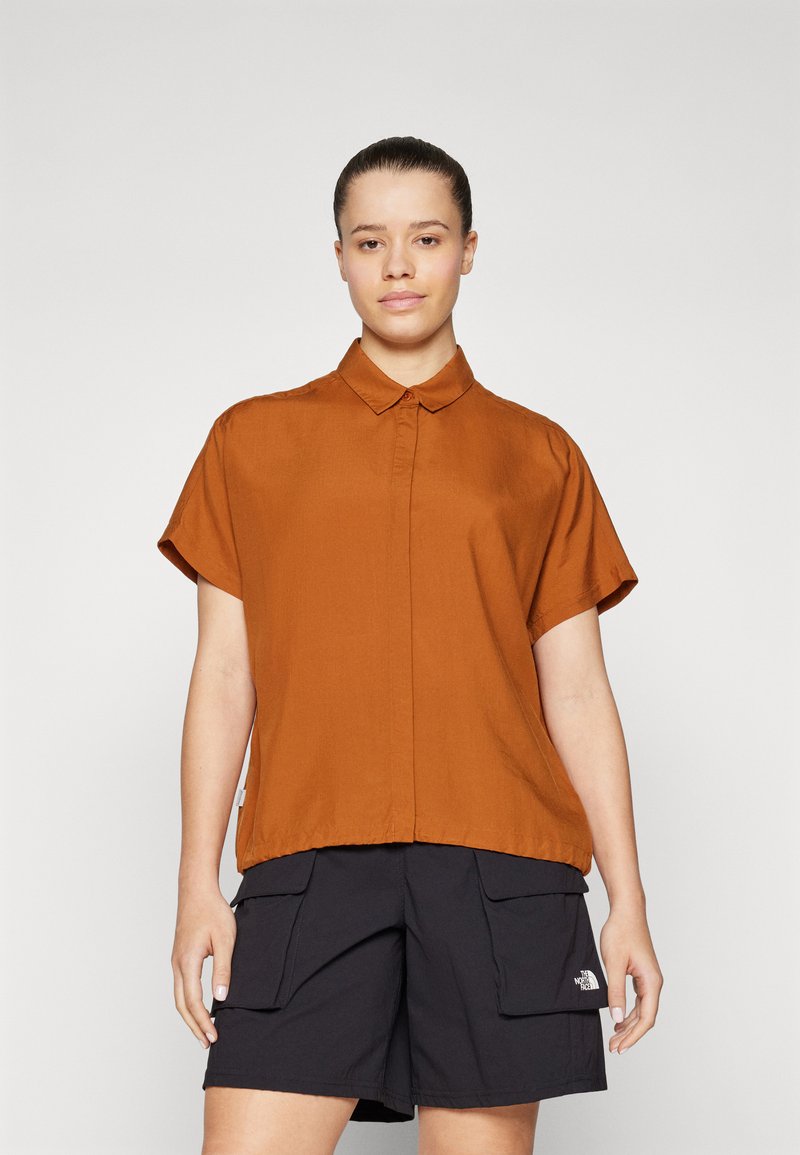 Short-sleeve collared shirt in burnt orange, featuring a button front and a relaxed fit, paired with black cargo shorts.