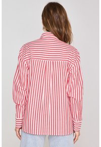 Camicia a righe rosse e bianche con colletto classico, polsini con bottone e un design sul retro plissettato, realizzata in tessuto morbido.