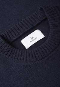 Granatowy sweter z dzianiny z ryflem przy okrągłym dekolcie. Posiada etykietę materiałową z nazwą marki "Matinique" umieszczoną w pobliżu kołnierza.