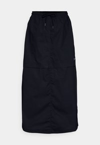 Falda negra de tela ligera, con una cinturilla elástica y cordón, aberturas laterales y una textura suave. Detalle sutil del logo.