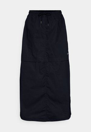 Falda negra de tela ligera, con una cinturilla elástica y cordón, aberturas laterales y una textura suave. Detalle sutil del logo.