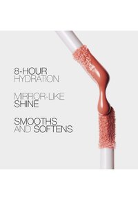Applicateur de gloss à lèvres avec gloss rose pêche sur fond blanc, le texte met en avant une hydratation de 8 heures, de la brillance et des bienfaits lissants.