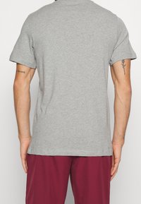 Grå kortærmet t-shirt lavet af bomuld med rund hals og en afslappet pasform. Bagsiden er glat uden grafik.