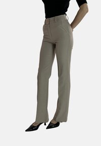 Beige op maat gemaakte broek met een hoge taille, zijzakken en een gladde textuur. Gelijkend met zwarte puntige hakken.